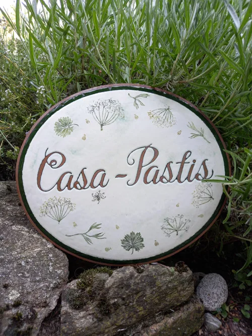 Ovales Schild „Casa Pastis“ mit botanischem Motiv.