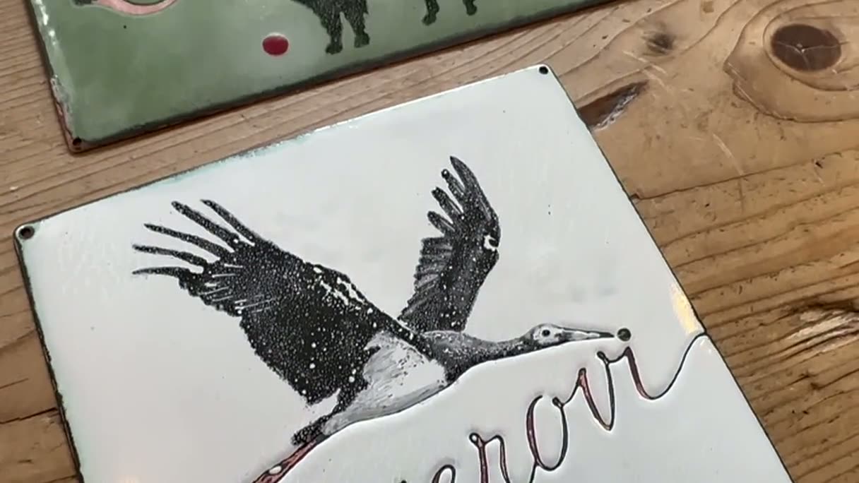 Nahaufnahme von zwei Emailleschildern auf dem Werktisch im Atelier